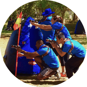 A group of young adults at a Team Building Event hide behind an inflatable bunker